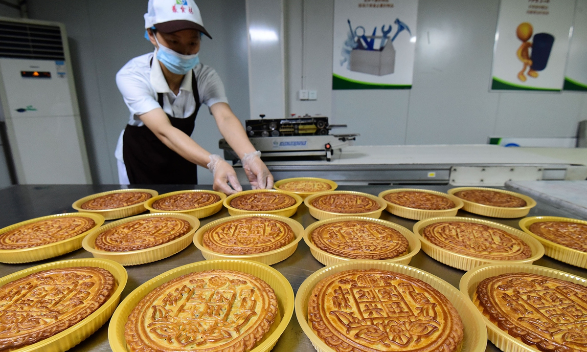 A worker displays mooncakes in Handan, North China's Hebei Province on August 16, 2022. As China's mid-Autumn Festival, which falls on September 10, draws near, food processing firms are operating in full swing to meet soaring market demand. Photo: cnsphoto
