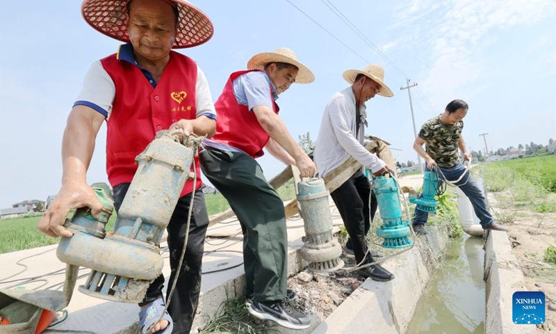 Volunteers lay pumping gears into a canal for irrigation in Xin'an Township, Deqing County, Huzhou City of east China's Zhejiang Province, Aug. 23, 2022. (Photo by Xie Shangguo/Xinhua)
