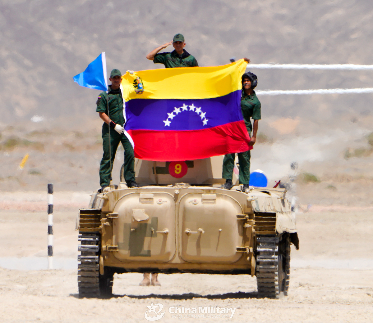 The infantry fighting vehicle crew of the Venezuelan team displays the national flag of Venezuela after the first round of individual race of the Suvorov Onslaught contest in Korla, China's Xinjiang Uygur Autonomous Region, on August 14, 2022. The Suvorov Onslaught of the International Army Games 2022 (IAG 2022) kicked off on August 14 with participation of six teams from five countries, namely China, Russia, Belarus, Iran and Venezuela. (Photo by Lin Yong)