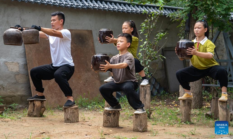 Liu Long and his children practice squat in Liuzhuang Village of Pizhou City, east China's Jiangsu Province, Aug. 16, 2022. Liu Long, 35, is a Chinese martial arts enthusiast. He found that his three children were also interested in martial arts and often imitated the action of him when he was practicing, so he began to take the three children to do martial arts training. Local villagers also sent their children to learn martial arts from Liu.(Photo: Xinhua)