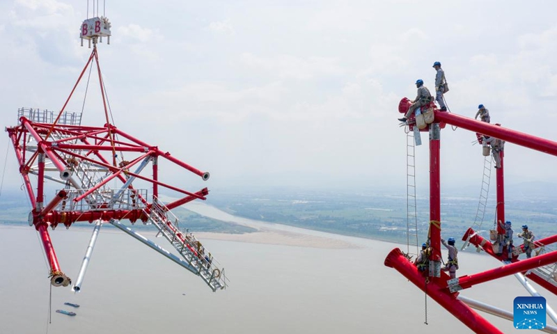 Aerial photo taken on Aug. 16, 2022 shows utility technicians working at the construction site of the north power transmission tower of the Baihetan-Zhejiang 800-kilovolt ultra-high-voltage (UHV) direct current power transmission project over the Yangtze River in Tongling, east China's Anhui Province.(Photo: Xinhua)
