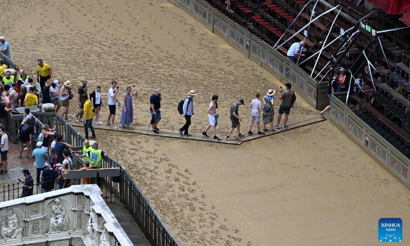 Spectators leave after the suspension of the horse race Palio in Siena, Italy, Aug. 16, 2022. The horse race Palio has been postponed to Aug. 17 due to the rain. The historical horse race Palio is held again this year after a two-year pause because of the COVID-19 pandemic. (Photo by Alberto Lingria/Xinhua)