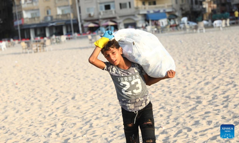 A child collects waste from the beach in Alexandria, Egypt, Aug. 13, 2022. On the beaches in the Egyptian city of Alexandria, a group of Egyptian young people are usually seen holding green and white plastic bags to collect the scattering waste.(Photo: Xinhua)