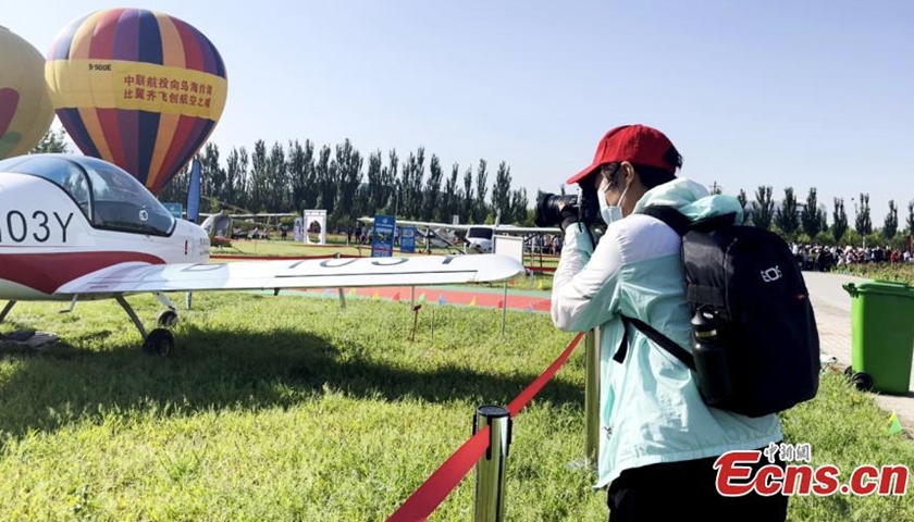 2022年8月17日，一名游客在中国内蒙古自治区2022乌海航空嘉年华上为展示的飞机拍照。（图片/中新社）
