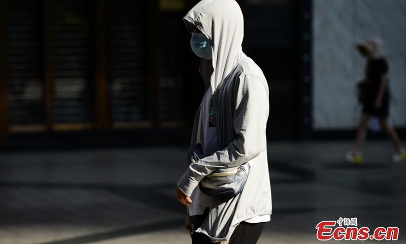 2022年8月17日，重庆，一名行人穿着防晒服在街上行走。（照片：中新社/何鹏磊）