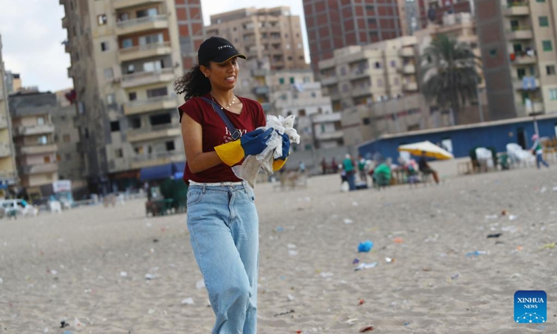 A woman collects waste from the beach in Alexandria, Egypt, Aug. 13, 2022. On the beaches in the Egyptian city of Alexandria, a group of Egyptian young people are usually seen holding green and white plastic bags to collect the scattering waste.(Photo: Xinhua)