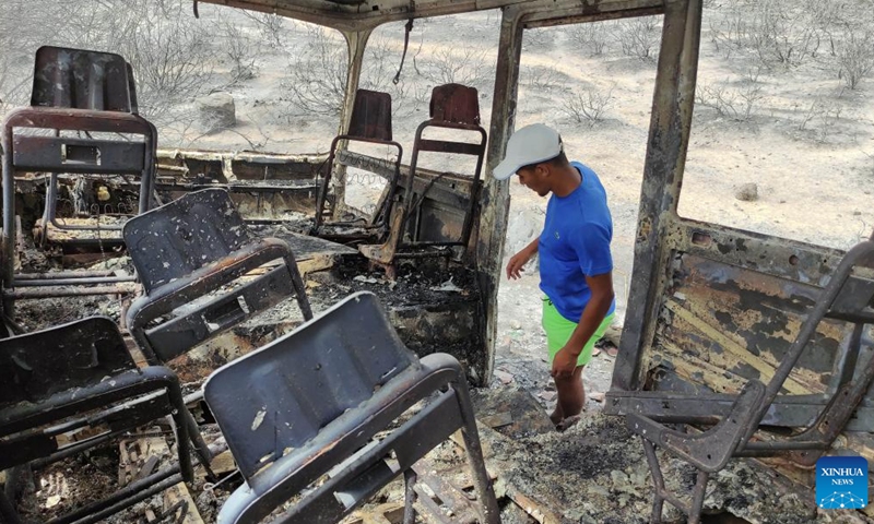 A man checks a vehicle damaged in a forest fire in El Tarf province, Algeria, on Aug. 18, 2022. At least 37 people were killed and 235 others injured in forest fires that have ravaged large parts of the country, said a statement of the Algerian civil protection authority on Thursday.(Photo: Xinhua)