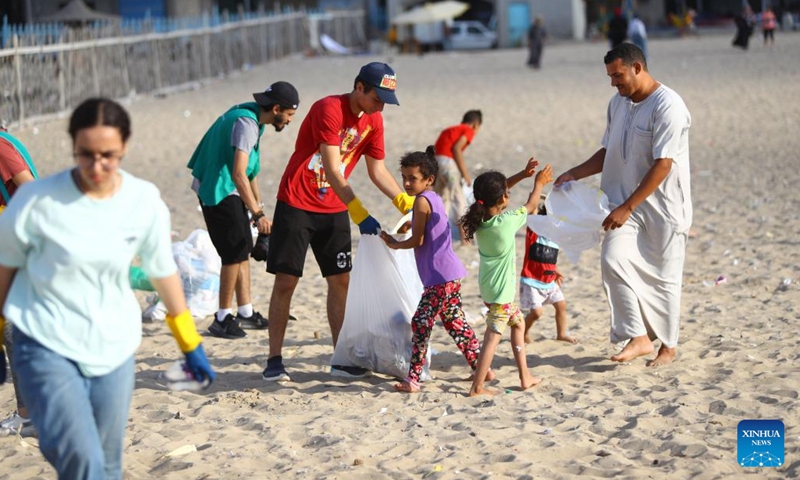 People collect waste from the beach in Alexandria, Egypt, Aug. 13, 2022. On the beaches in the Egyptian city of Alexandria, a group of Egyptian young people are usually seen holding green and white plastic bags to collect the scattering waste. They are participants in a cleanup campaign organized by Banlastic Egypt, an environmental project launched by a group of youth in the Mediterranean city.(Photo: Xinhua)