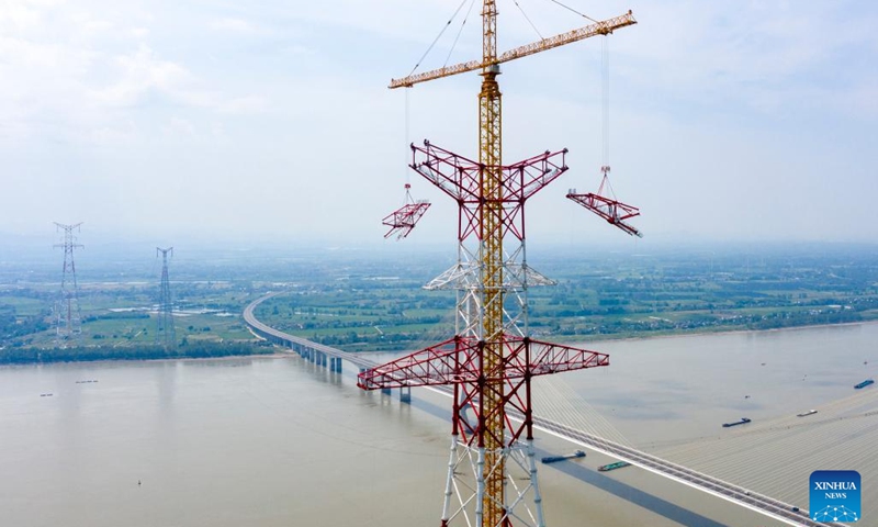 Aerial photo taken on Aug. 16, 2022 shows utility technicians working at the construction site of the north power transmission tower of the Baihetan-Zhejiang 800-kilovolt ultra-high-voltage (UHV) direct current power transmission project over the Yangtze River in Tongling, east China's Anhui Province.(Photo: Xinhua)