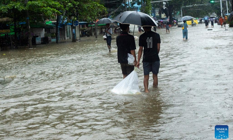 People wade through a flooded street after heavy rains in Yangon, Myanmar, Aug. 17, 2022.(Photo: Xinhua)