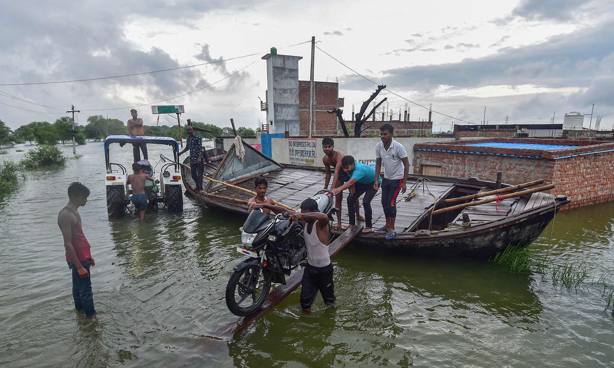 Villagers use a boat to commute at a waterlogged area caused by floodwaters after a rise in water level of River Yamuna following monsoon rains at Badara Sanuti Village, near Allahabad, India, on August 20, 2022. Photo: VCG