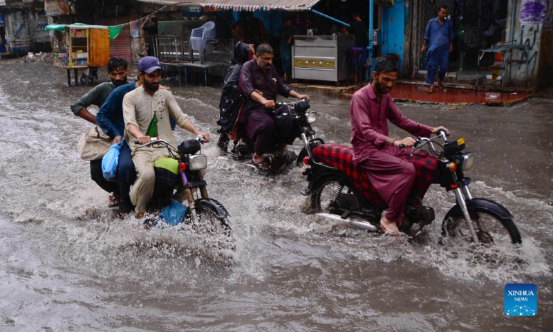 People ride motorbikes through flood water after heavy rains in southern Pakistan's Hyderabad on Aug. 23, 2022. As many as 903 people were killed, nearly 1,300 injured and thousands left homeless as heavy monsoon rains and flash floods continued to play havoc in Pakistan since mid-June, the National Disaster Management Authority (NDMA) said on Wednesday. (Str/Xinhua)