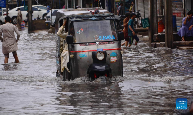 An auto rickshaw moves through flood water after heavy rains in southern Pakistan's Hyderabad on Aug. 23, 2022. As many as 903 people were killed, nearly 1,300 injured and thousands left homeless as heavy monsoon rains and flash floods continued to play havoc in Pakistan since mid-June, the National Disaster Management Authority (NDMA) said on Wednesday. (Str/Xinhua)