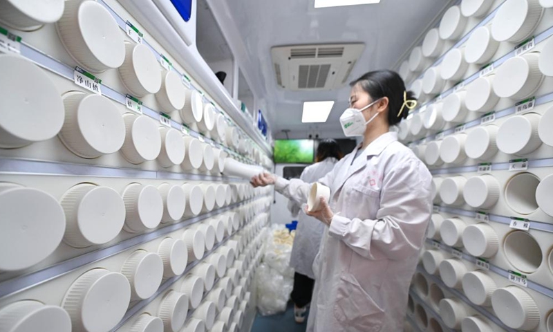 A pharmacist takes a bottle containing concentrated herbal granules to prepare traditional Chinese medicine (TCM) doses at a mobile TCM pharmacy in Sanya, south China's Hainan province, Aug. 20, 2022.Photo:Xinhua
