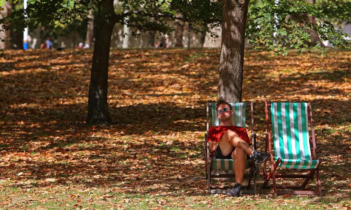 A man sits on a deckchair among brown leaves fallen from the trees in St James' Park in London, on August 24, 2022. Photo: AFP