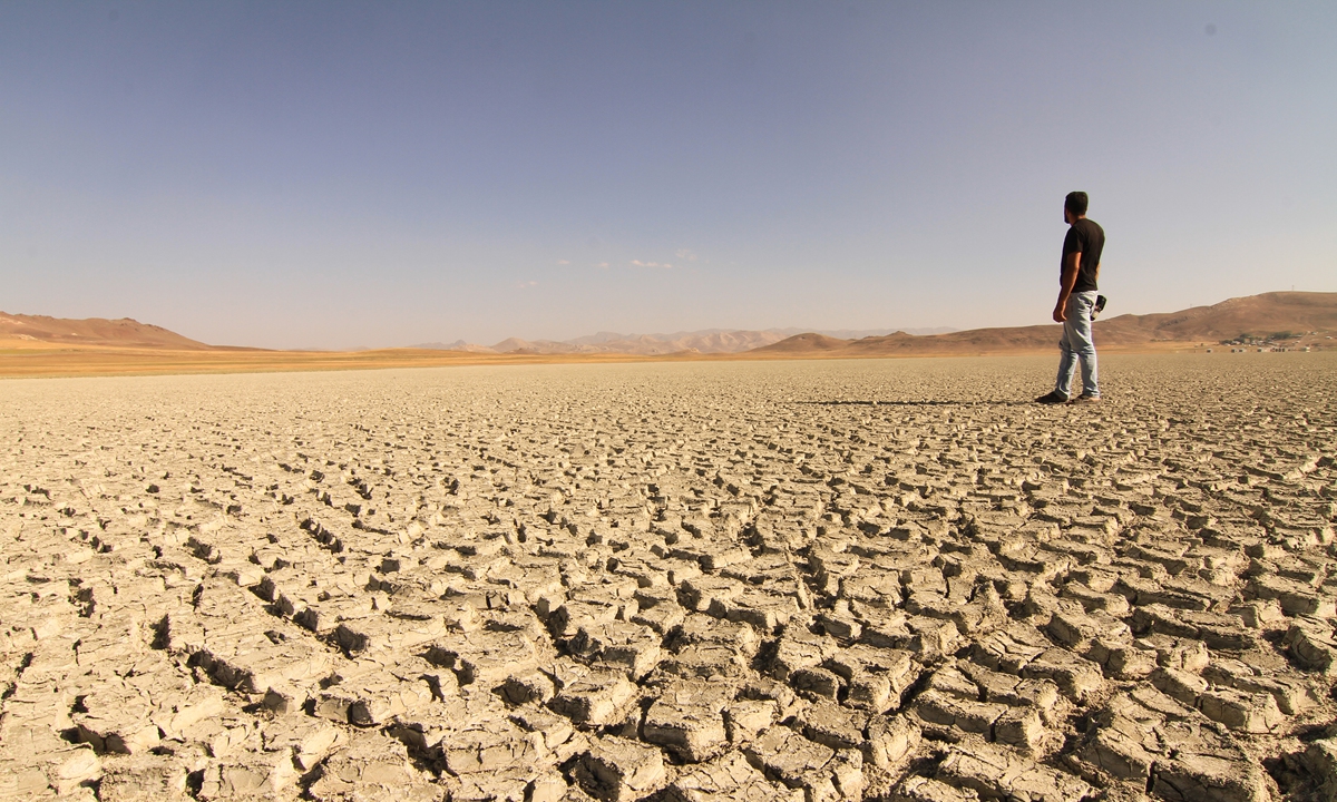 A man stands on a cracked soil of Lake Akgol, dried out due to heat wave and vaporization, in the Ozalp district of Van Province, Turkey, on August 10, 2022. Photo: VCG