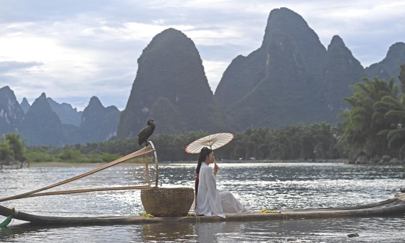 A visitor poses for photos at Xingping Town in Yangshuo County of Guilin, south China's Guangxi Zhuang Autonomous Region, Aug. 25, 2022.Photo:Xinhua