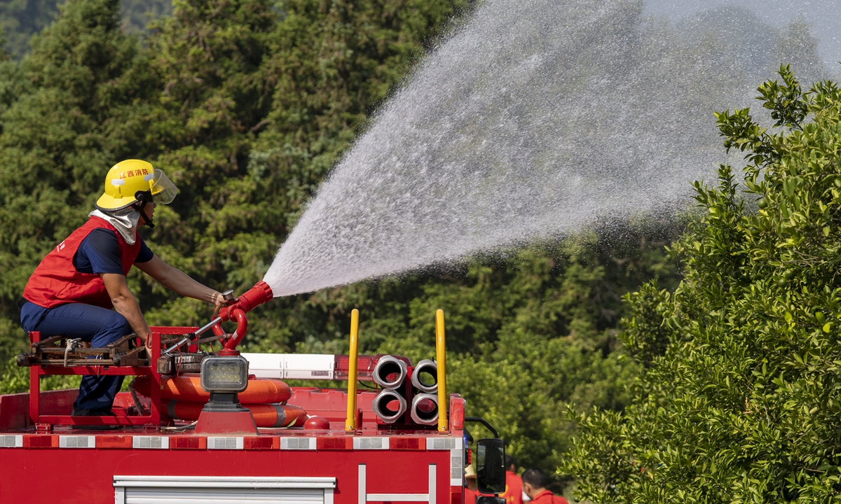 A firefighter waters an orchard in Xinyu city, East China's Jiangxi Province, on August 28, 2022. Local authorities are organizing officials, volunteers and firefighters to use sprinklers, water pumps, and fire trucks to irrigate orchards and minimize losses for fruit farmers amid low rainfall and record-breaking heat. Photo: VCG