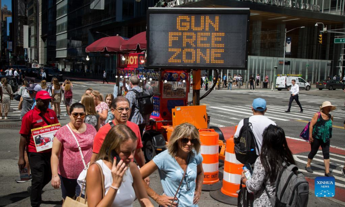 Passersby walk past a gun-free zone signboard near Times Square in New York, the United States, Sep 1, 2022. Photo:Xinhua