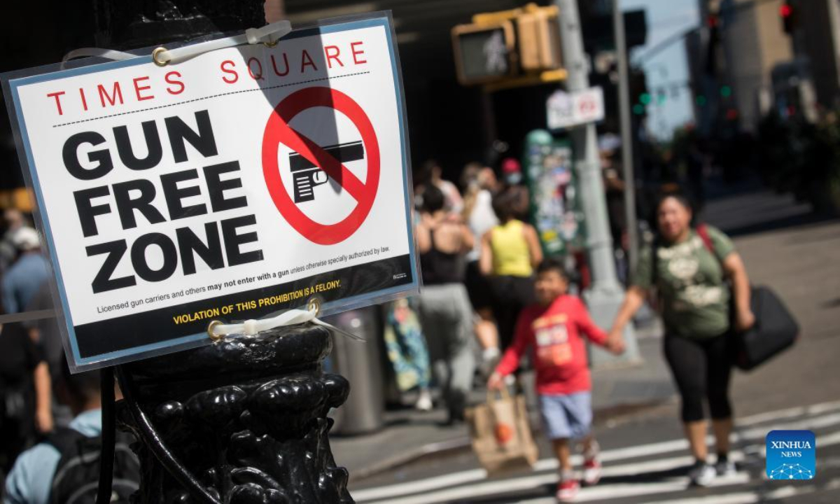 Passersby walk past a gun-free zone signboard near Times Square in New York, the United States, Sep 1, 2022. Photo:Xinhua