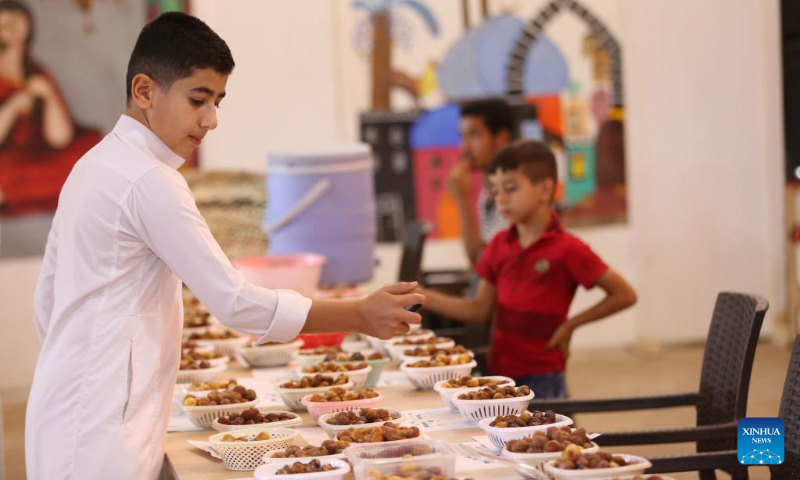 A boy takes pictures with his mobile phone during the sixth annual date festival in Dhuluiya, Iraq, on Sept. 9, 2022. (Xinhua/Khalil Dawood)