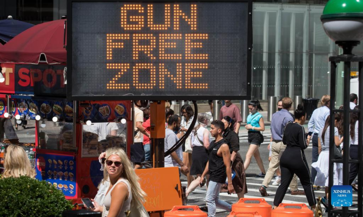 Passersby walk past a gun-free zone signboard near Times Square in New York, the United States, Sep 1, 2022. Photo:Xinhua