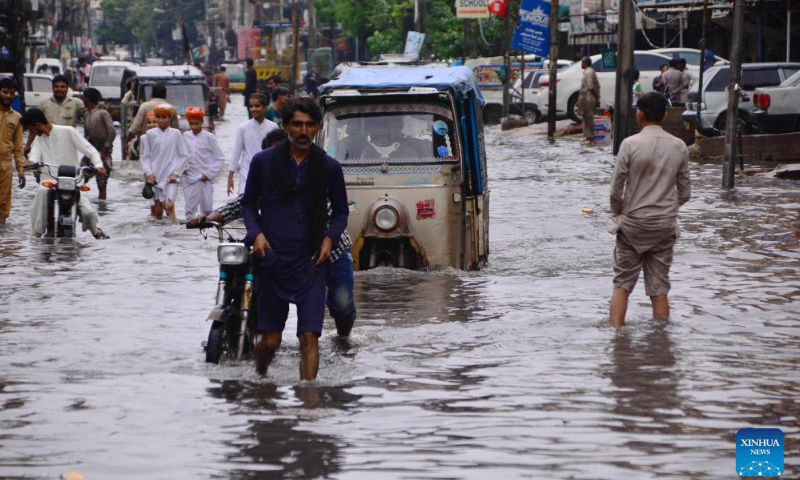 People wade through flood water after heavy rains in southern Pakistan's Hyderabad on August 23, 2022. Photo: Xinhua