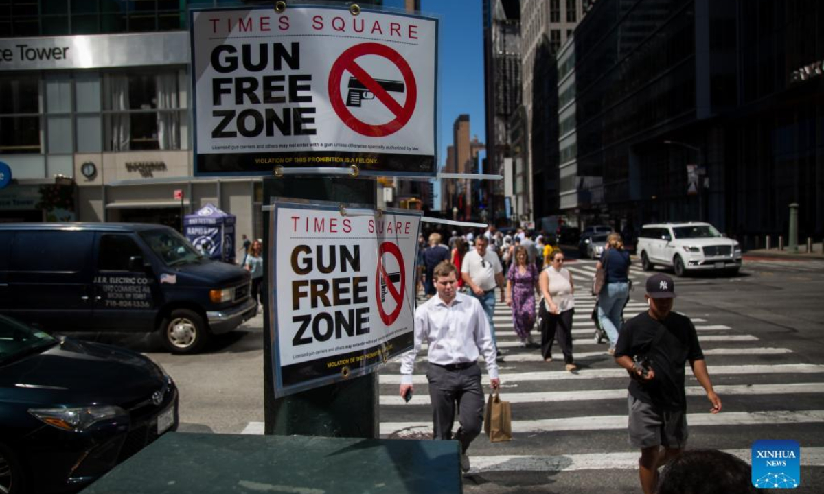 Passersby walk past a gun-free zone signboard near Times Square in New York, the United States, Sep 1, 2022. Photo:Xinhua