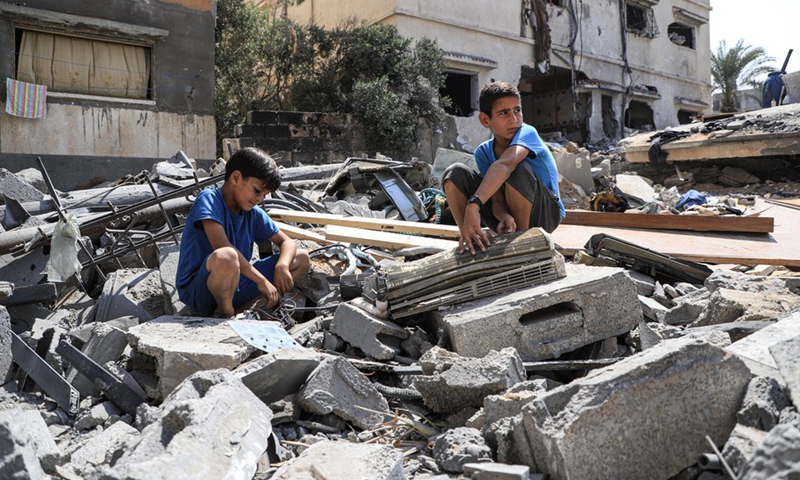 Palestinian children sit on the rubbles of their house which was damaged by Israeli airstrike in Gaza City, on Aug. 9, 2022.(Photo: Xinhua)