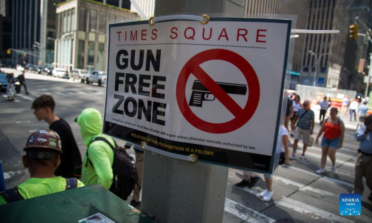 Passersby walk past a gun-free zone signboard near Times Square in New York, the United States, Sep 1, 2022. Photo:Xinhua