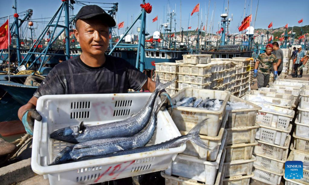 A fisher display his catches at Jimiya fishing port in Xihai'an (West Coast) New Area in Qingdao, east China's Shandong Province, Sep 7, 2022. Fully loaded fishing ships returned to the port from their first sails after a four-month fishing ban lifted not long ago. Photo:Xinhua