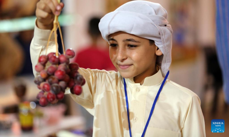A boy poses with a cluster of dates at the sixth annual date festival in Dhuluiya, Iraq, on Sept. 9, 2022. (Xinhua/Khalil Dawood)