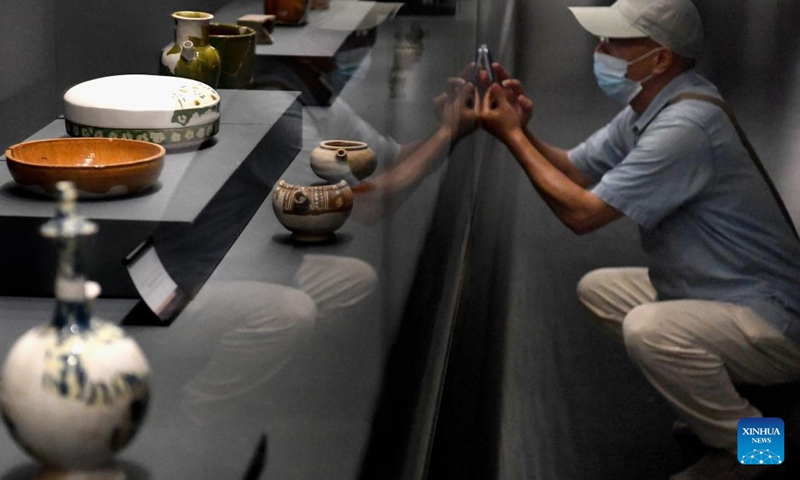 A visitor takes photos of exhibits during a joint exhibition of tri-colored glazed potteries in Zhengzhou, central China's Henan Province, Aug. 30, 2022. The joint exhibition displayed more than 300 tri-colored glazed potteries of the Tang Dynasty (618-907) unearthed from 10 kilns of five provinces in China.(Photo: Xinhua)