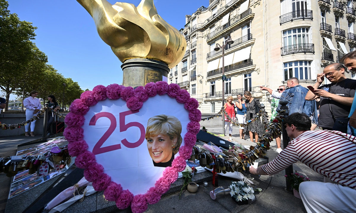 A woman leaves a note as people gather to commemorate the 25th anniversary of the death of Lady Diana Spencer on August 31, 2022 at the 