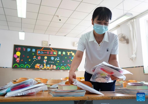 A teacher distributes textbooks in the Experimental Primary School of RDFZ (The High School Affiliated to Renmin University of China) in Haidian District of Beijing, capital of China, Aug. 30, 2022. Schools in Zhongguancun area of Haidian District have organized staff members to make full preparation for the upcoming new semester. (Xinhua/Ren Chao)

