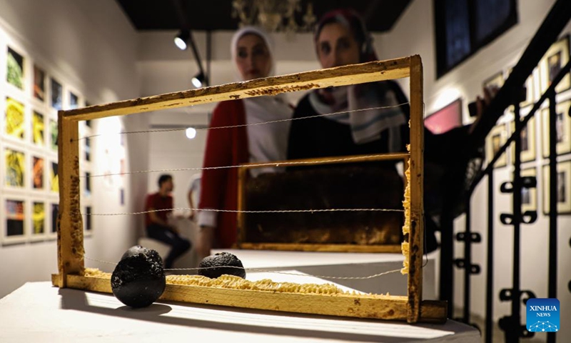 Palestinian people view an artwork during an exhibition called No One Yearns for Pain at Shababek for Contemporary Art in Gaza City, on Aug. 31, 2022.(Photo: Xinhua)