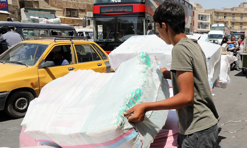 A boy loads goods onto a cart in al-Rasafi Square in central Baghdad, Iraq, on Aug. 29, 2022.(Photo: Xinhua)