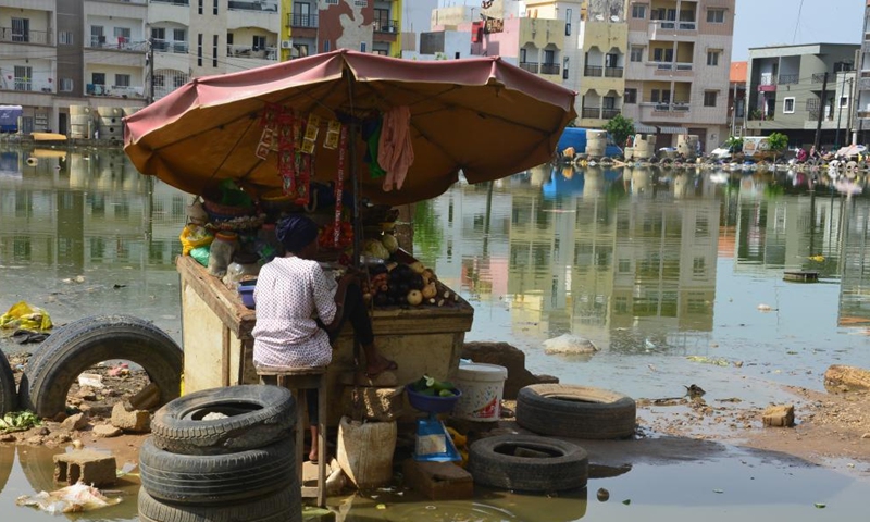 A woman waits for customers after torrential rain in Dakar, Senegal, on Sept. 3, 2022.Photo:Xinhua