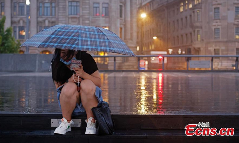 A visitor sits in the rain on the Bund in Shanghai, Sept. 4, 2022.Photo:China News Service