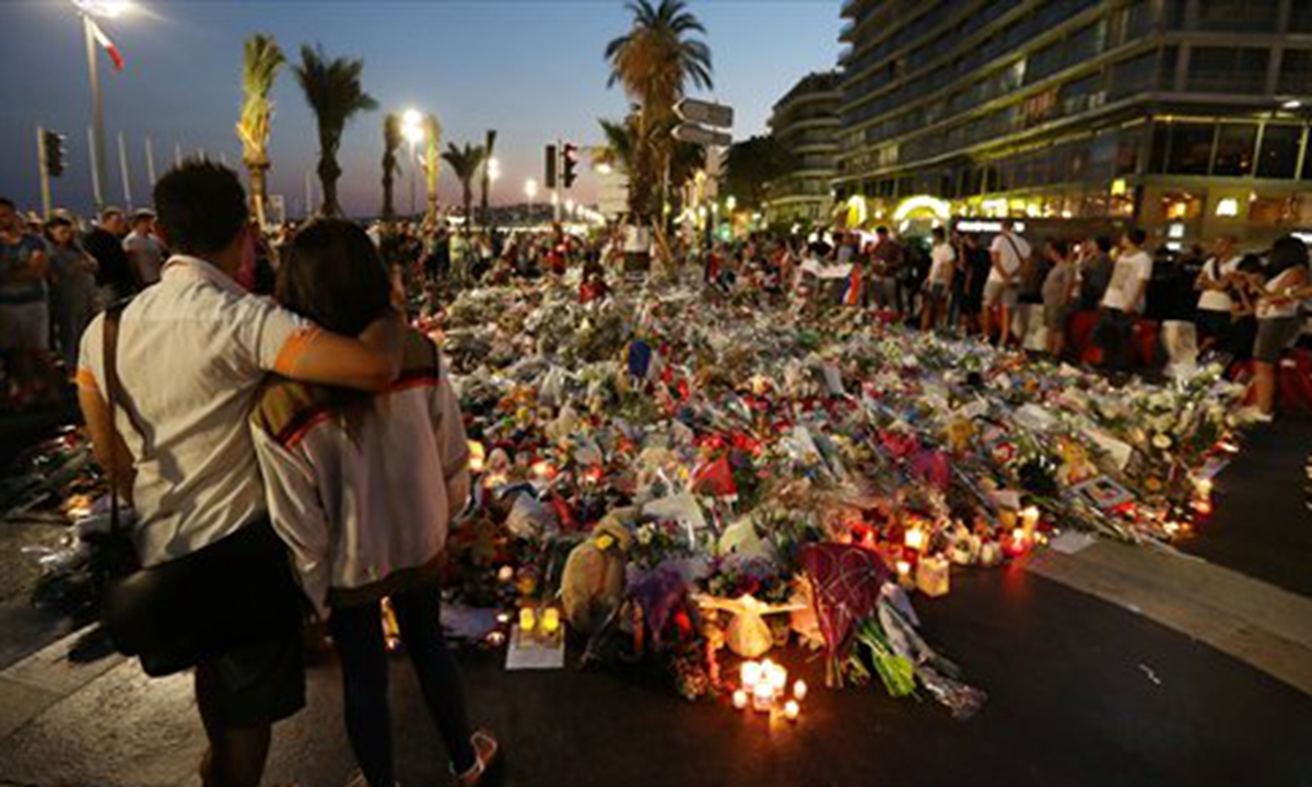 People stand in front of flowers, candles and messages laid at a makeshift memorial in Nice on July 18, in tribute to the victims of the deadly attack on the Promenade des Anglais seafront that killed 84 people. Photo: CFP