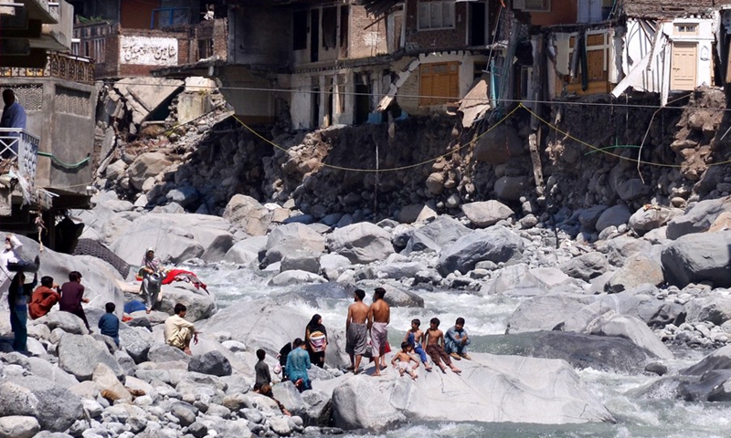 Flood-affected people are seen in front of damaged buildings after flash flood in Bahrain area of northwest Pakistan's Swat district on Sept. 5, 2022.(Photo: Xinhua)