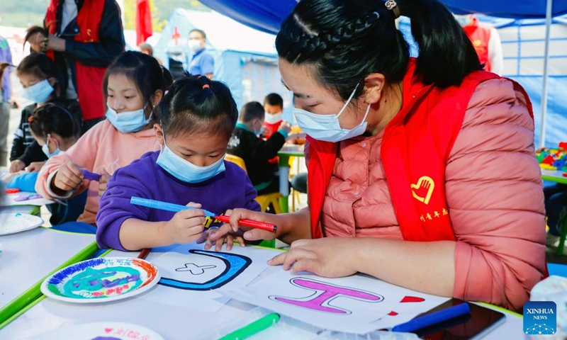 A girl draws pictures with a volunteer at a children's center at a quake relief shelter in Moxi Town of Luding County, southwest China's Sichuan Province, Sept. 7, 2022. A children's center has been built up at a quake relief shelter in Moxi Town to take care of children affected by the earthquake.(Photo: Xinhua)