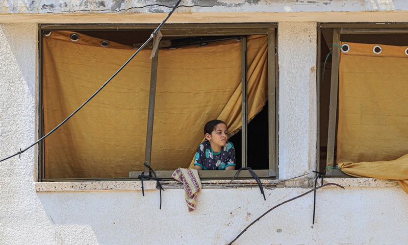 A girl looks from her house window, which was damaged by Israeli airstrike in Gaza City, on Aug. 9, 2022. (Photo: Xinhua)