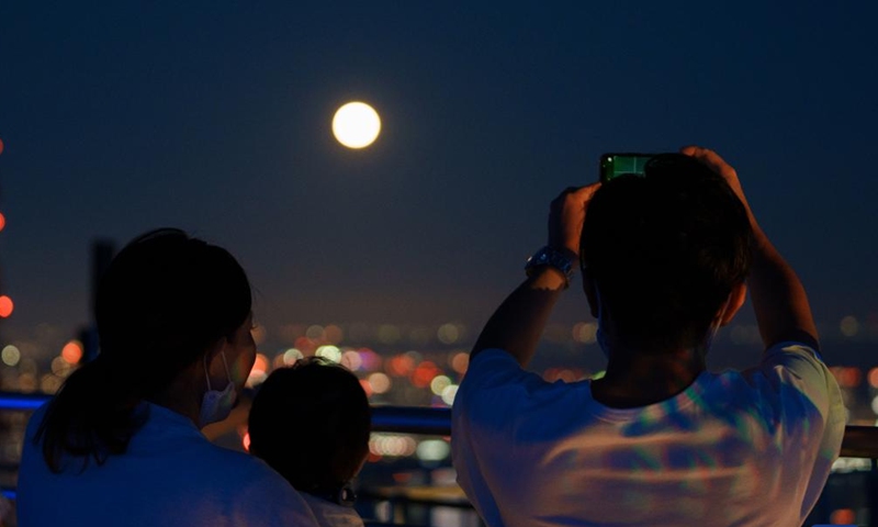 People watch a full moon at Roppongi Hills Mori Tower in Tokyo, Japan, Sept. 10, 2022.Photo:Xinhua