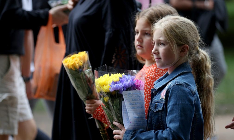 Two girls hold flowers as they walk to Buckingham Palace to commemorate the late Queen Elizabeth II in London, Britain, Sept. 10, 2022.Photo:Xinhua