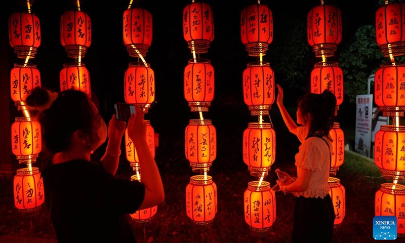 A visitor poses for a photo with Mid-Autumn Festival light installations at the Tengwang Pavilion scenic spot in Nanchang, capital of east China's Jiangxi Province, Sept. 10, 2022.Photo:Xinhua