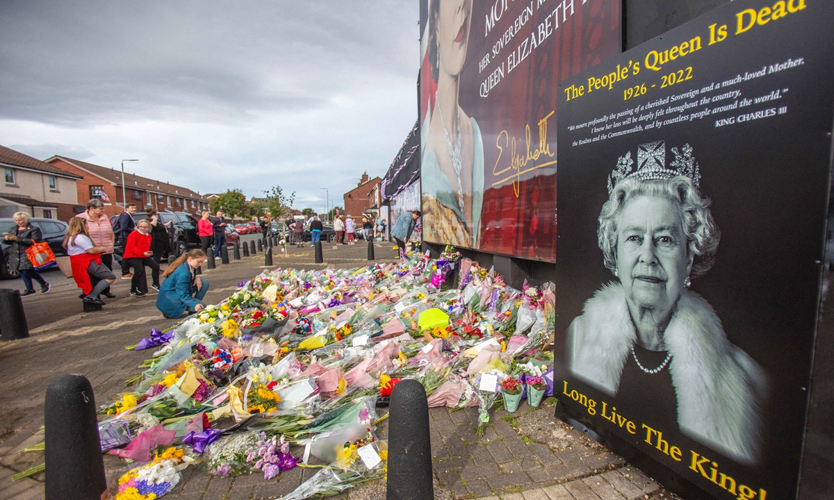 People gather in front of flowers and tributes placed by a mural on the Shankill road, in Belfast, Northern Irland on September 9, 2022, a day after Queen Elizabeth II died at the age of 96. Photo: AFP