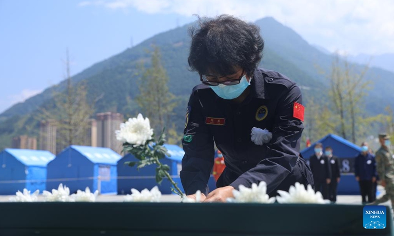 A rescue worker lays a flower to mourn for the victims of the earthquake during a memorial service in Shimian County of Ya'an City, southwest China's Sichuan Province, Sept. 12, 2022.Photo:Xinhua