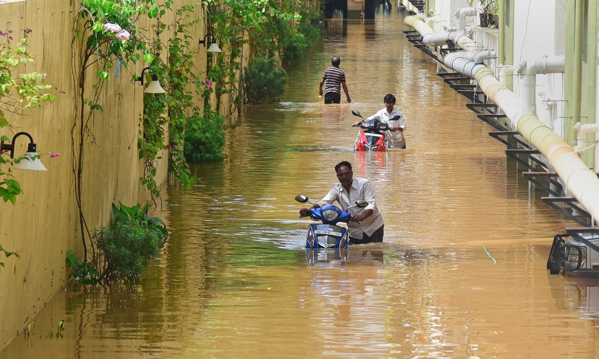 Men push their motorbikes along a waterlogged basement in Bengaluru, India, on September 6, 2022. Photo: AFP 
