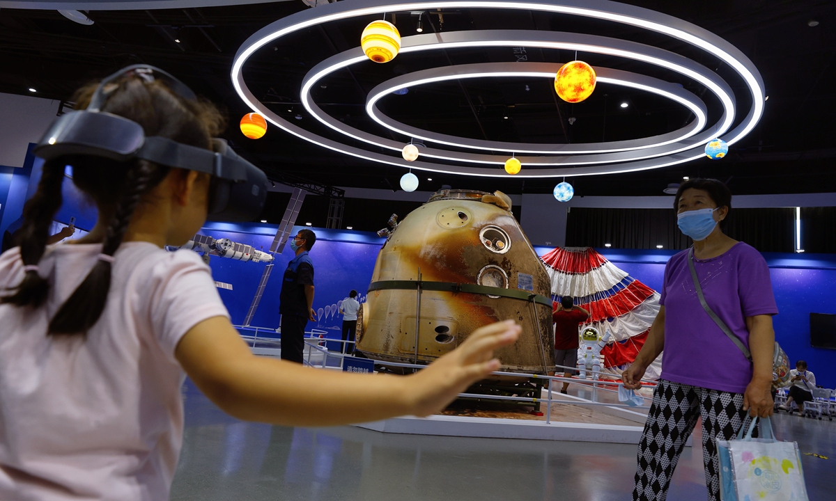 A child tries out a device in an exhibition hall where the Shenzhou-13 manned spacecraft re-entry module is displayed to the public for the first time at the Beijing Science Center on September 15, 2022. Photo: IC